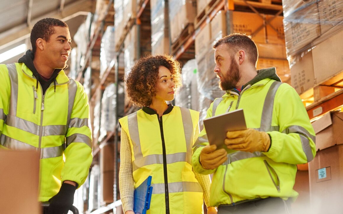 § Personen unterhalten sich in einer Lager- und Logistikhalle